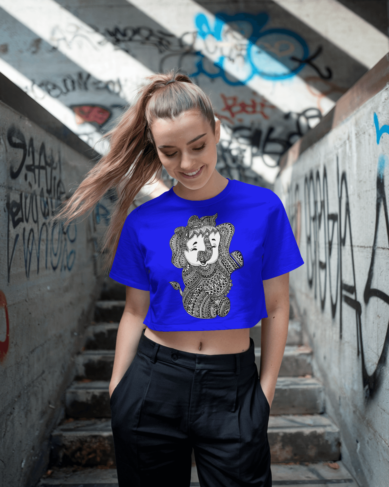 Woman wearing a blue t-shirt with a graphic design in an urban setting with graffiti.