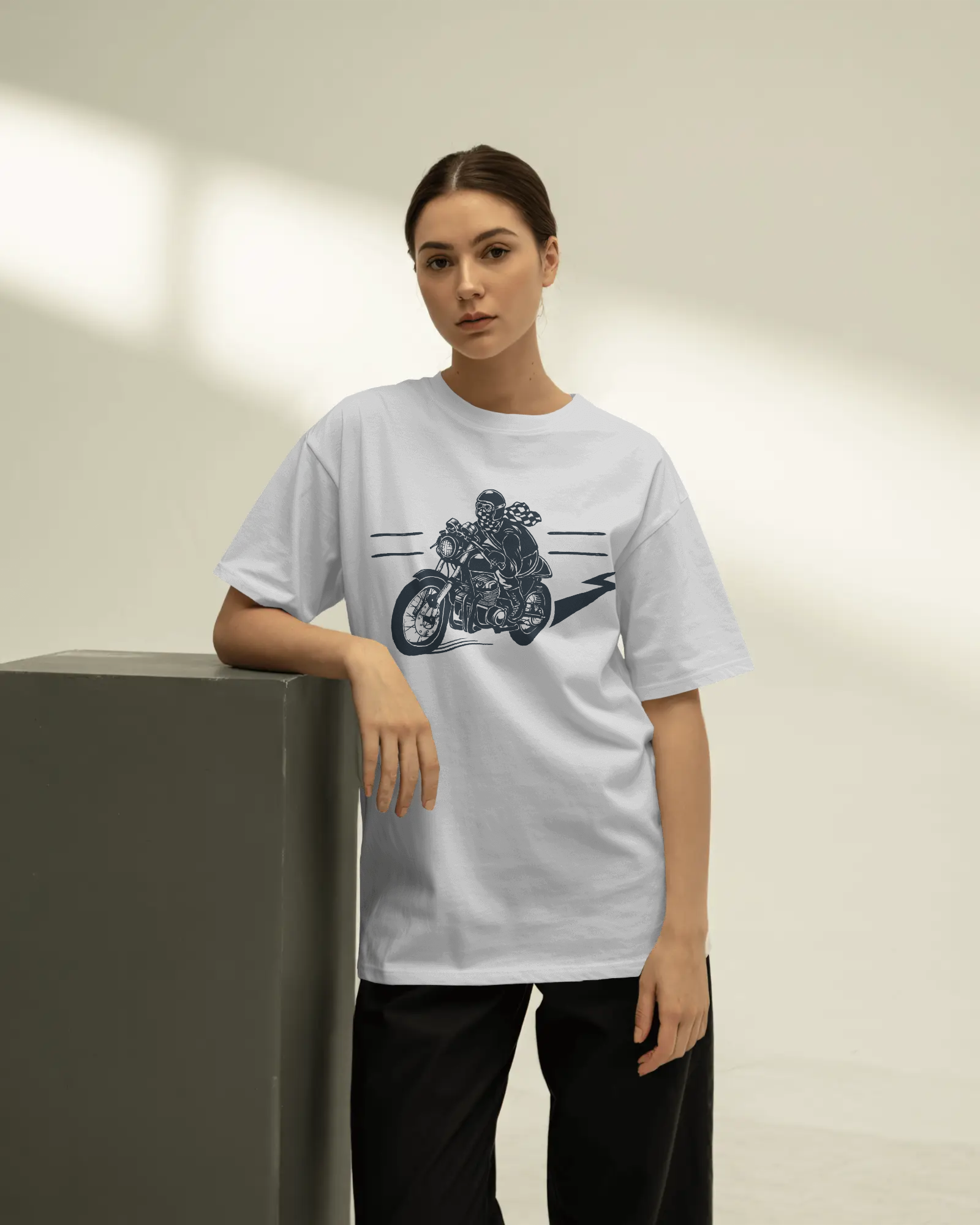 Person wearing a white t-shirt with a motorcycle graphic on a neutral background