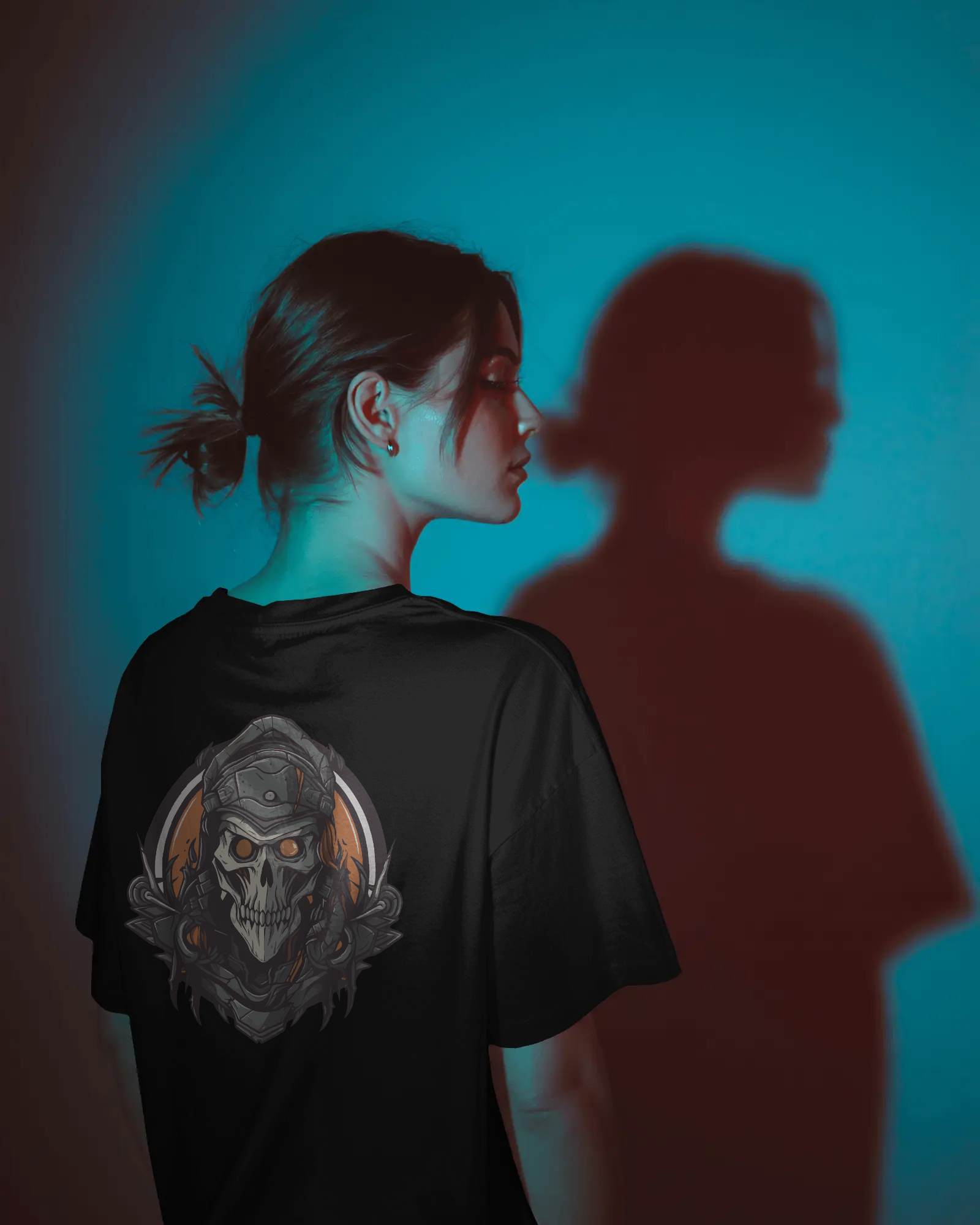 Person wearing a black t-shirt with a skull design, standing against a blue background.