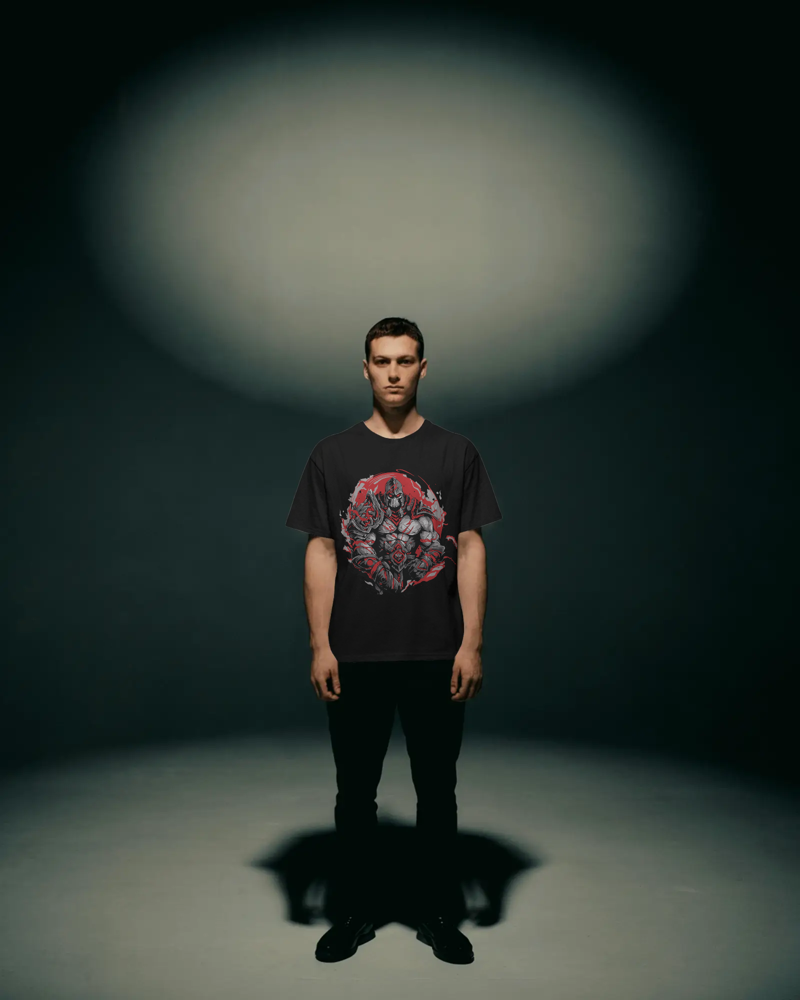 Man wearing a black t-shirt with a graphic design standing in a dark room with a spotlight on him.