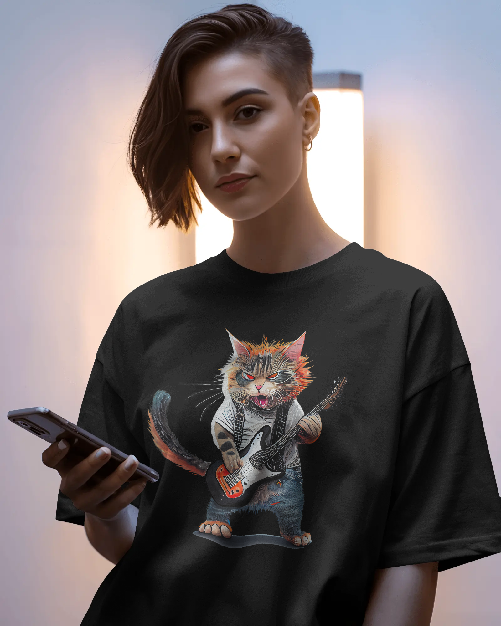 Person wearing a black t-shirt with a graphic of a cat playing guitar, holding a phone.