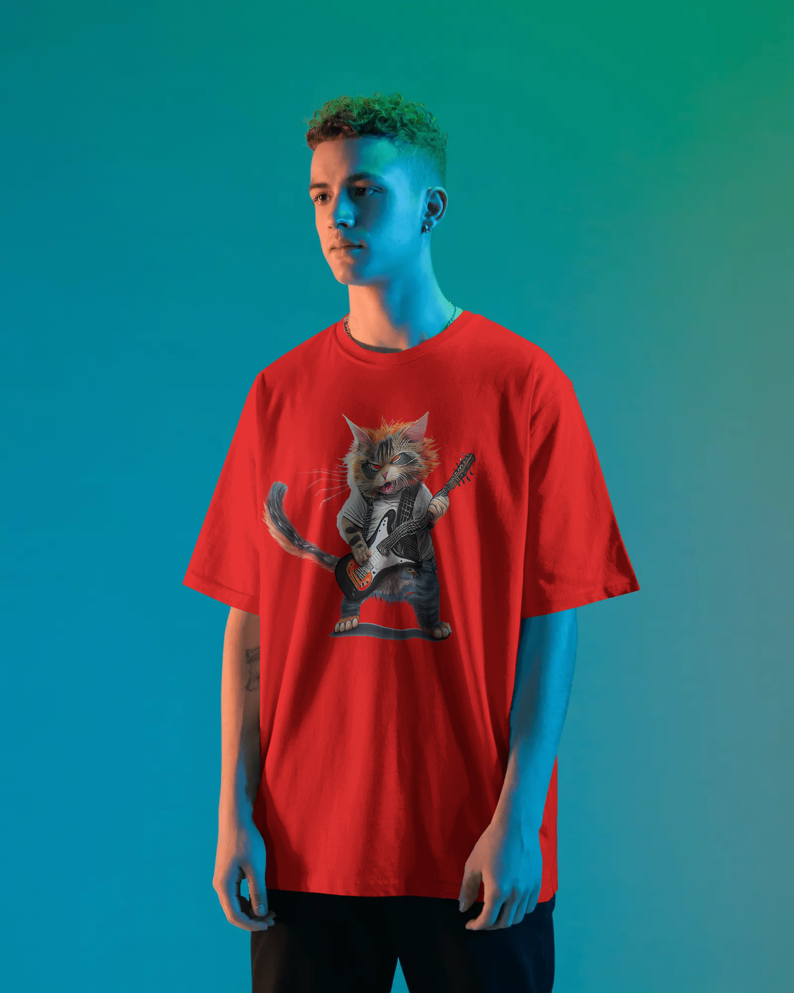 red oversized T-shirt featuring a rockstar cat graphic holding a guitar, standing in a studio with vibrant blue and green lighting.
