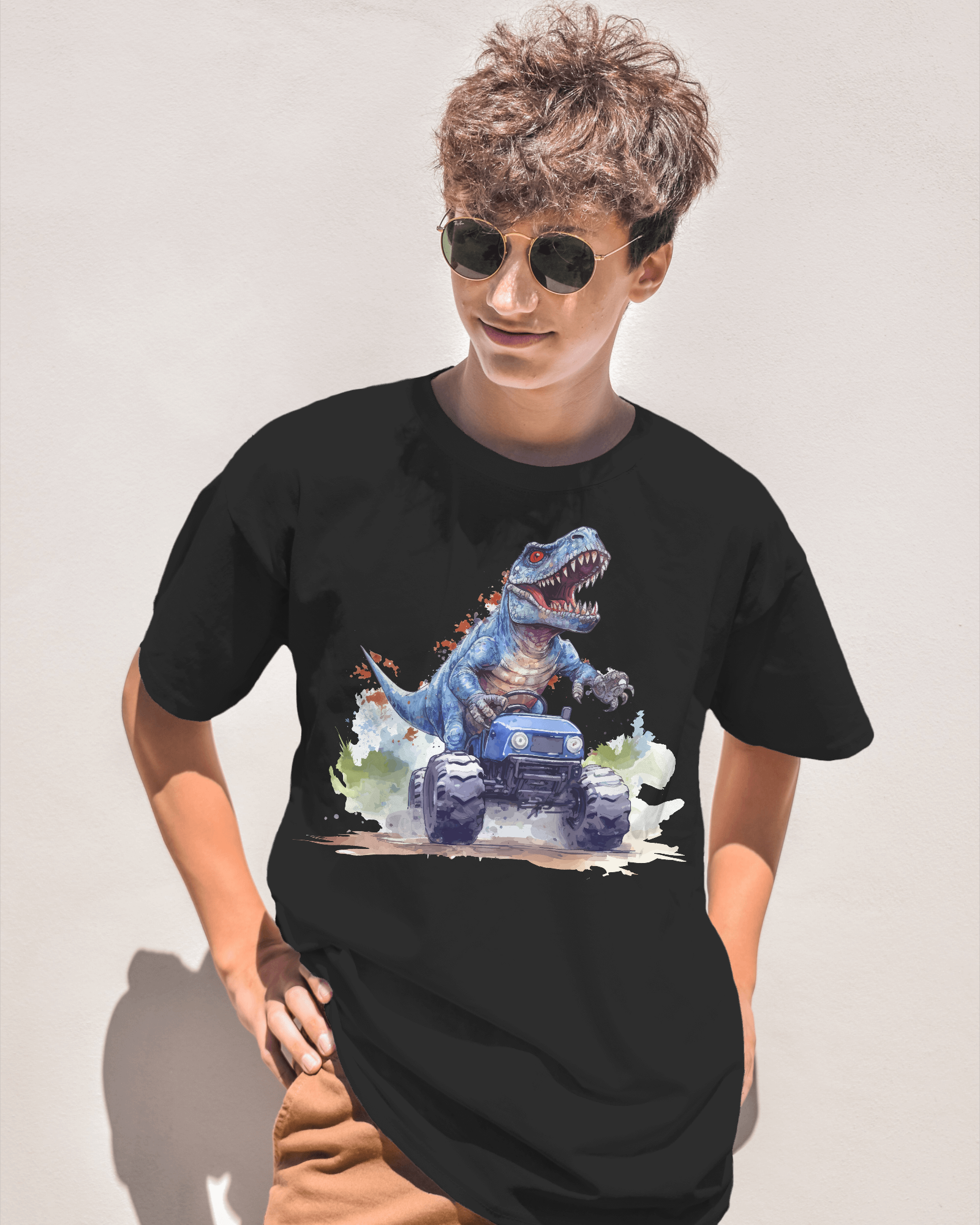 A person wearing a black oversized T-shirt featuring a fierce blue T-Rex riding a monster truck in a colorful action design, standing outdoors in sunlight.