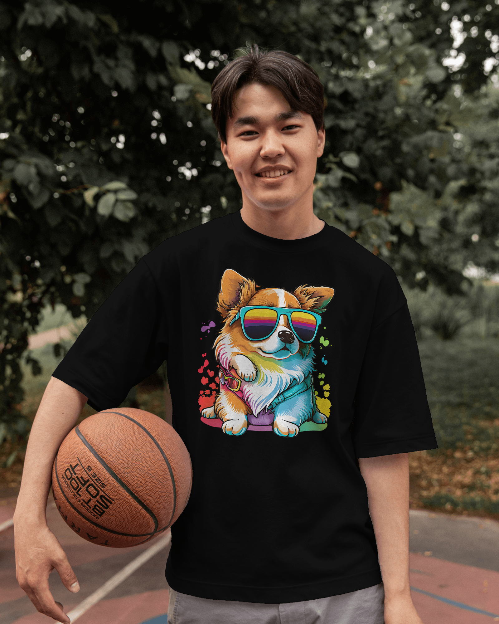 Person wearing a black t-shirt with a colorful dog graphic holding a basketball outdoors.