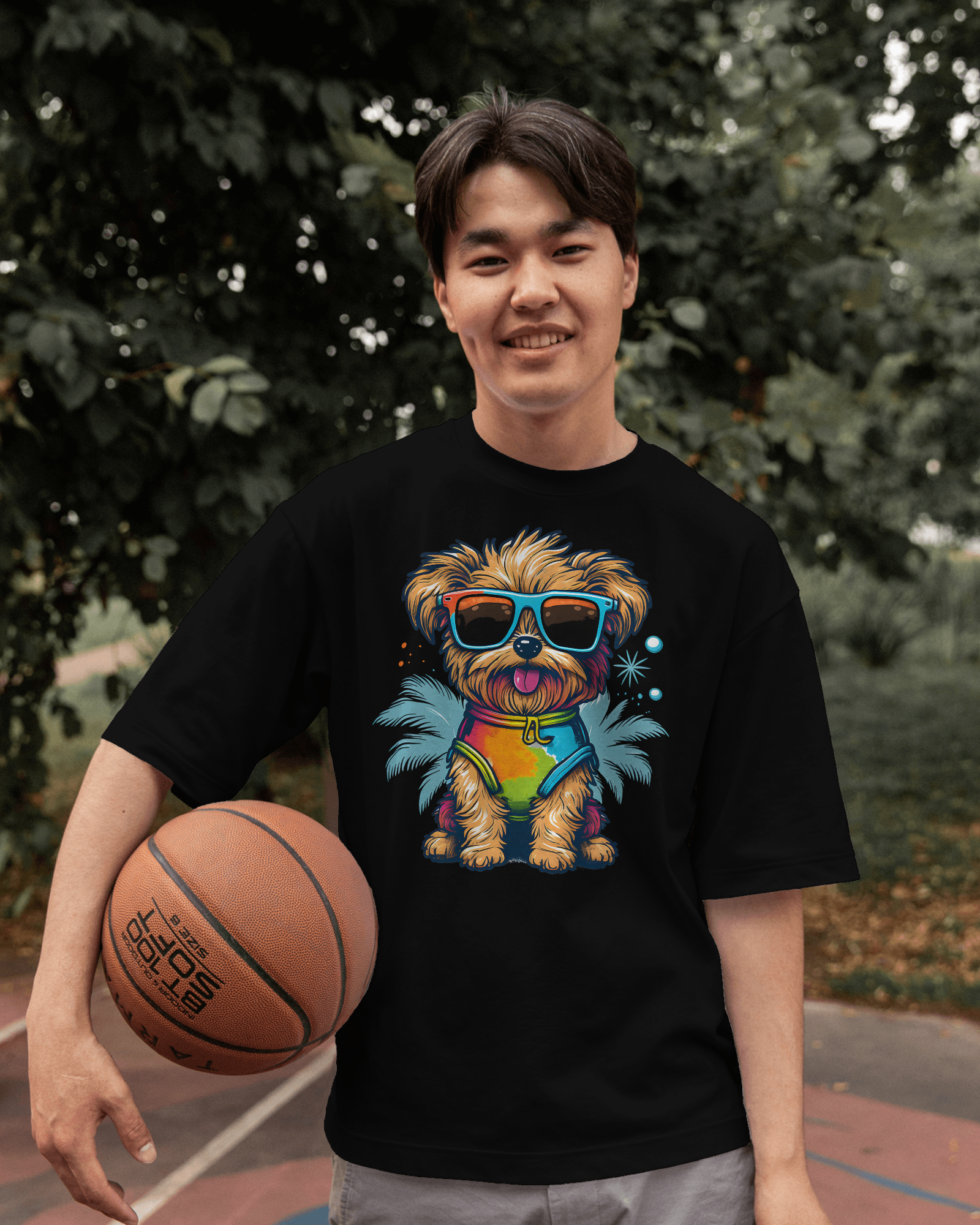 Person wearing a black t-shirt with a colorful dog graphic holding a basketball outdoors.