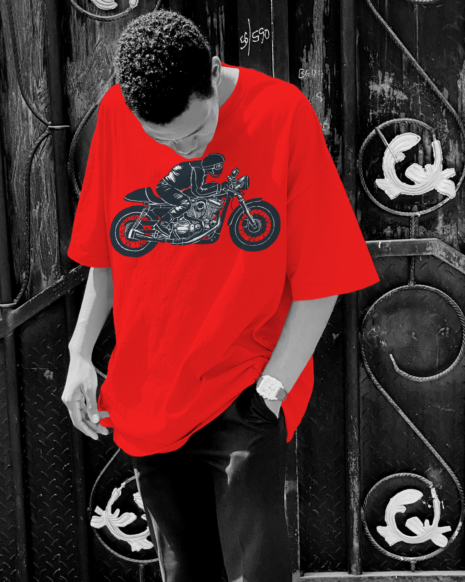 Person wearing a red t-shirt with a motorcycle graphic in front of a black and white door.