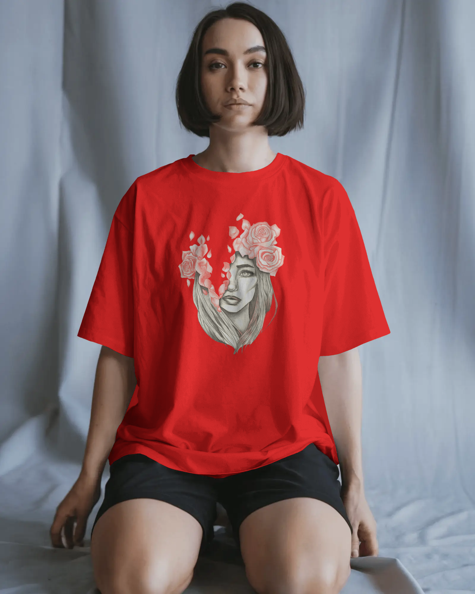 Person wearing a red t-shirt with a graphic design of a face with flowers on a plain background