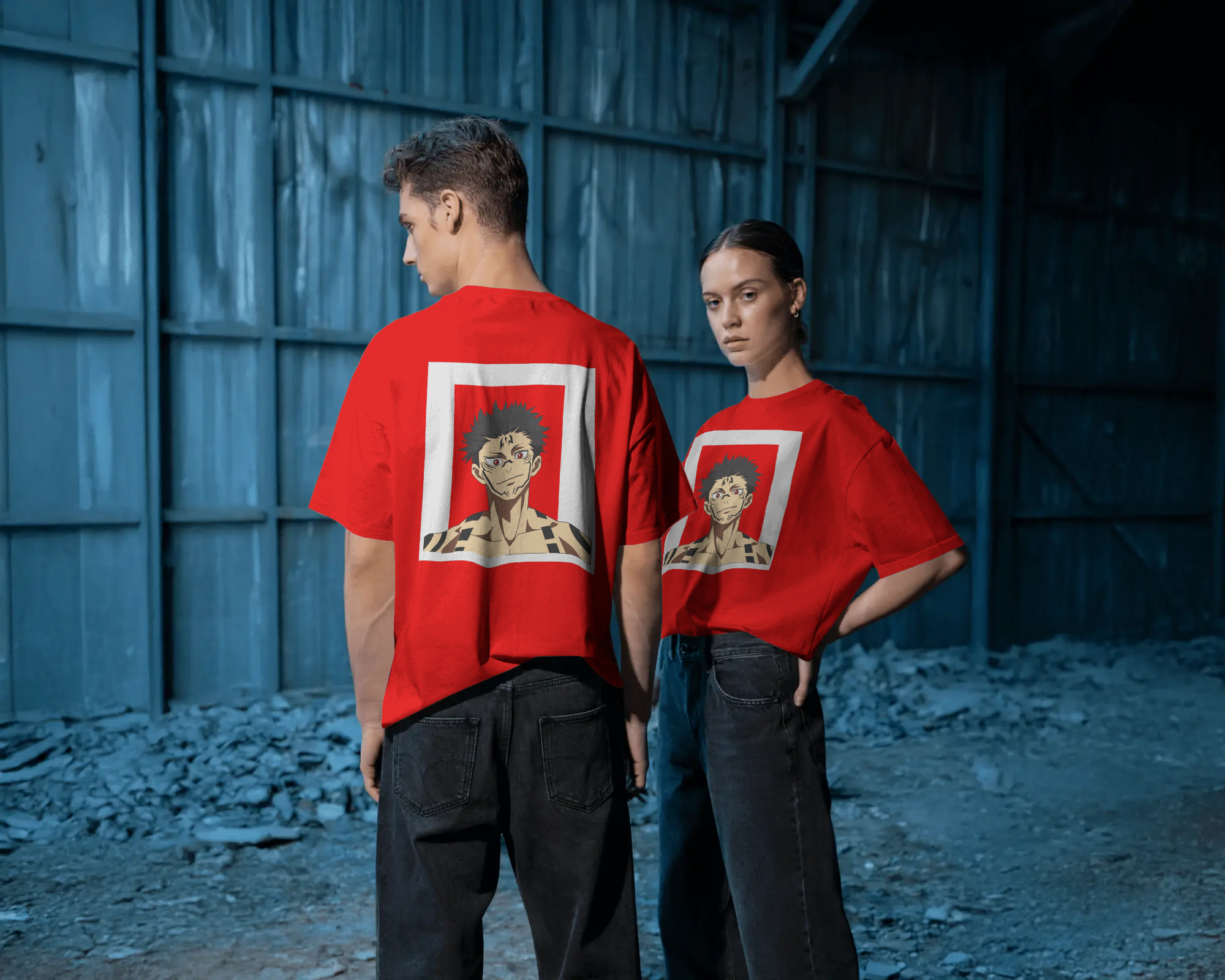 Two people wearing red t-shirts with graphic designs in a dark, industrial setting.