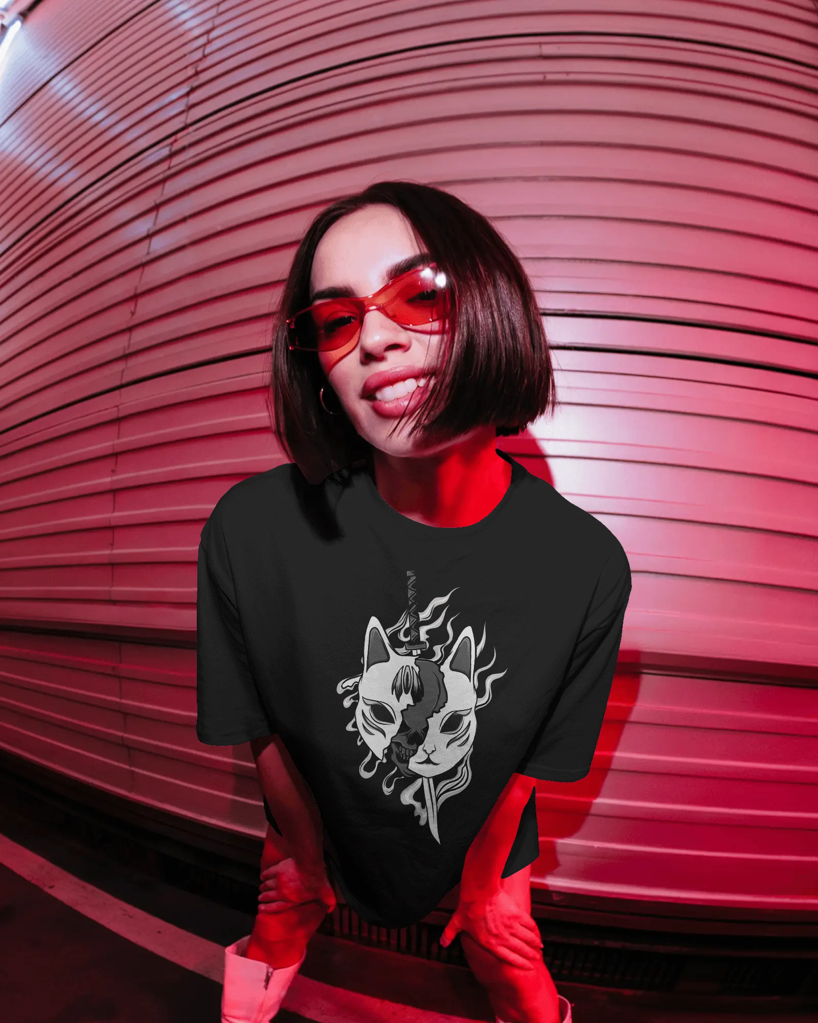 Person wearing a black t-shirt with a graphic design in front of a red metallic wall.