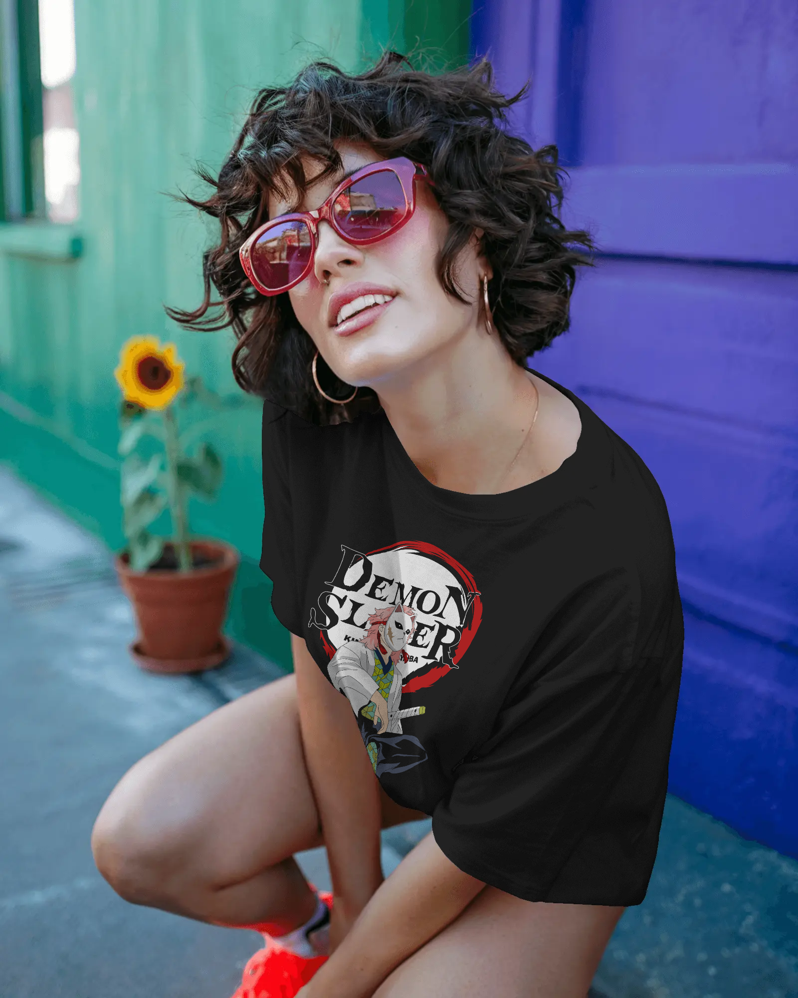 Woman wearing a black t-shirt with a graphic design in front of a colorful wall.