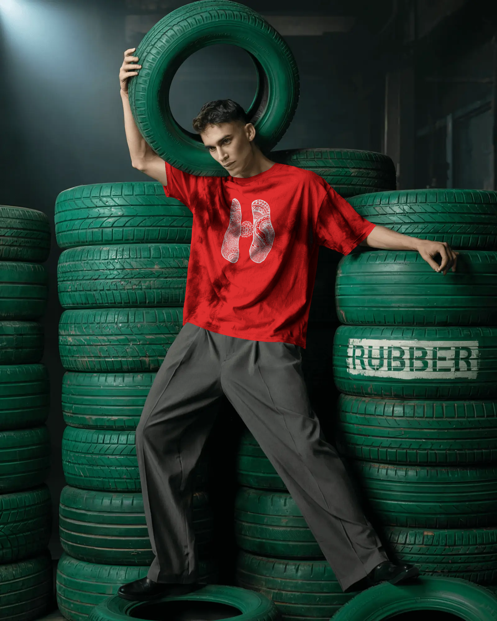 Person in a red shirt and gray pants standing among green tires with 'Rubber' text.