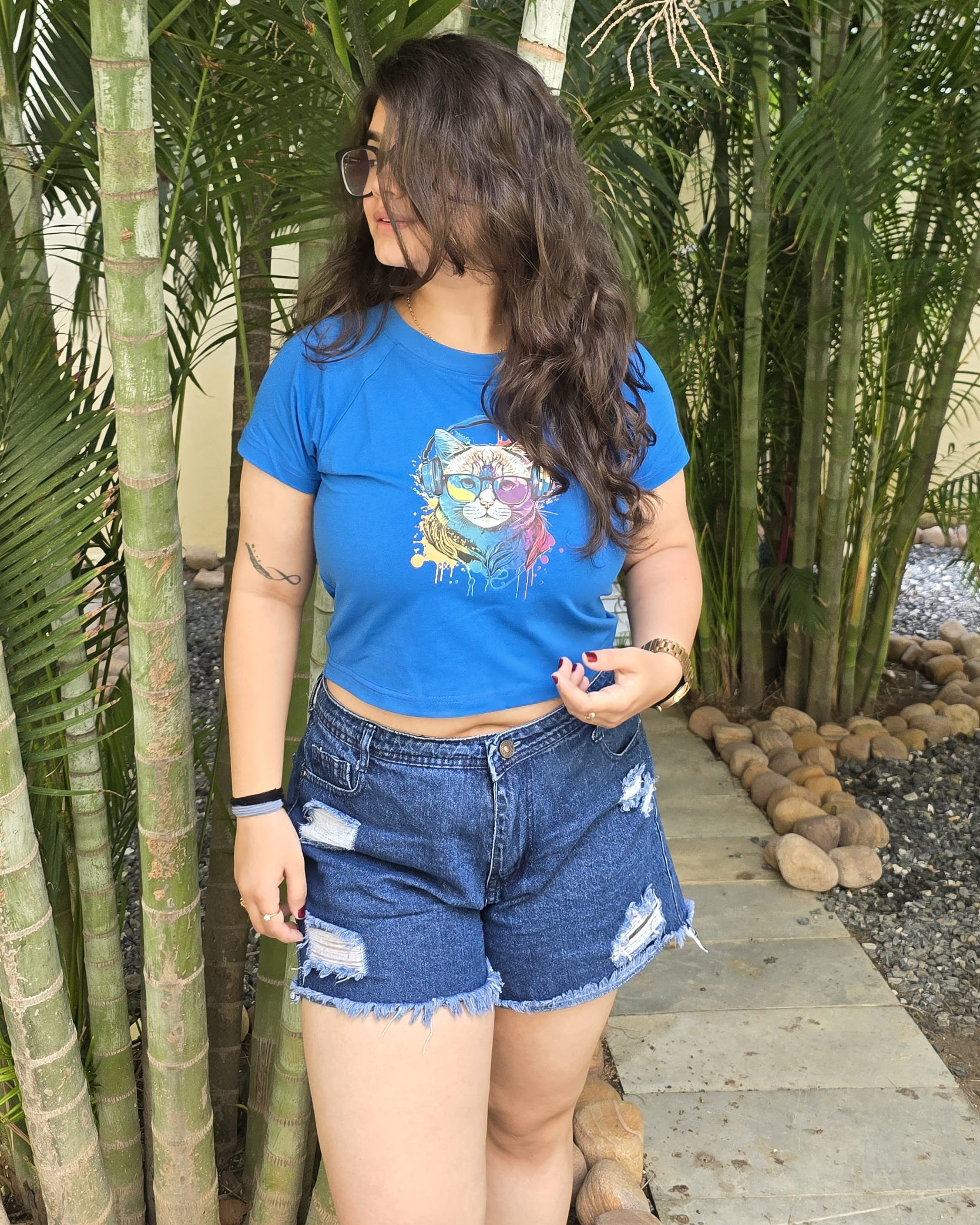 Blue crop top with colorful cat wearing headphones and sunglasses graphic print, front view