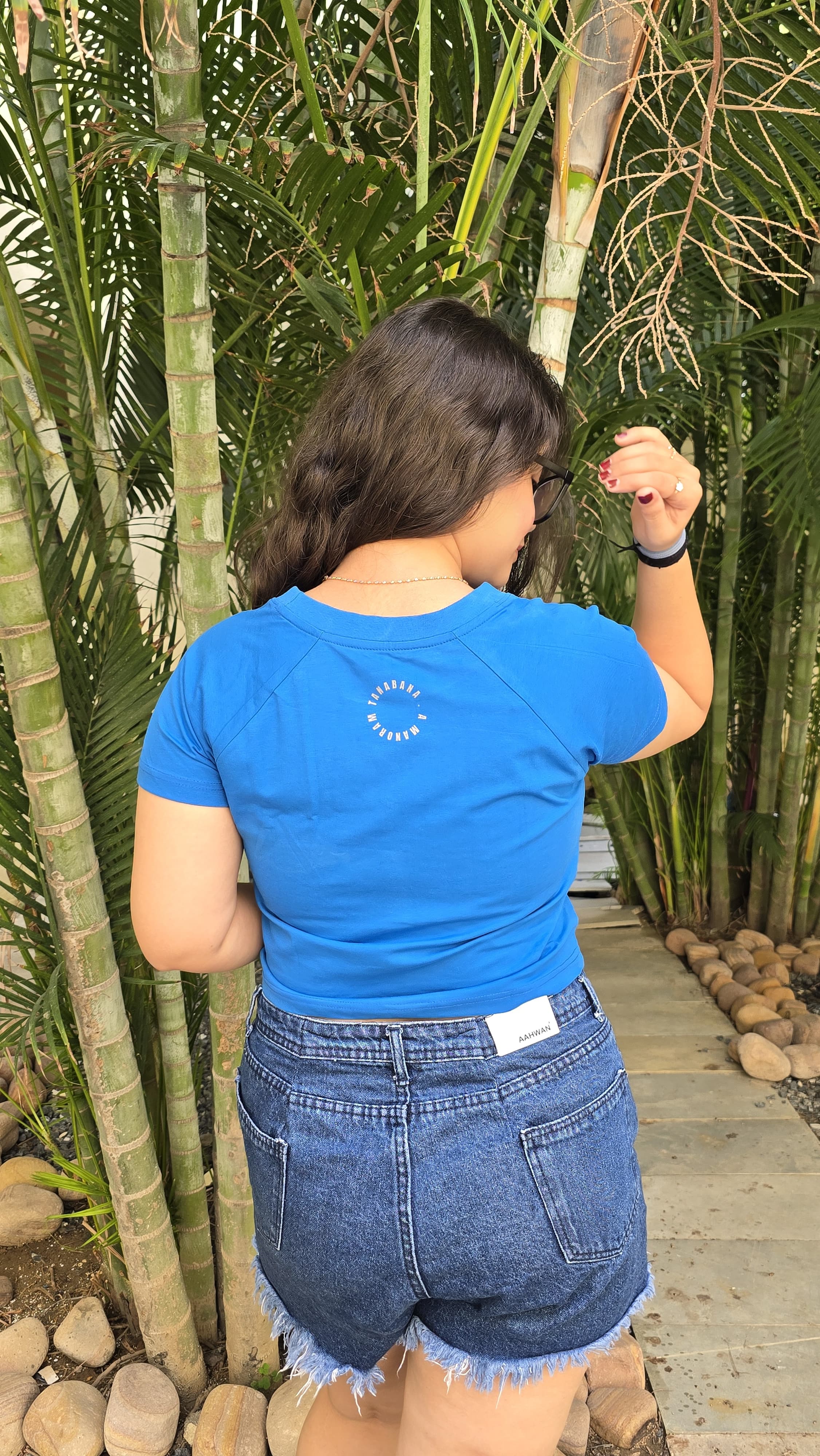 Blue crop top with colorful cat wearing headphones and sunglasses graphic print, back view