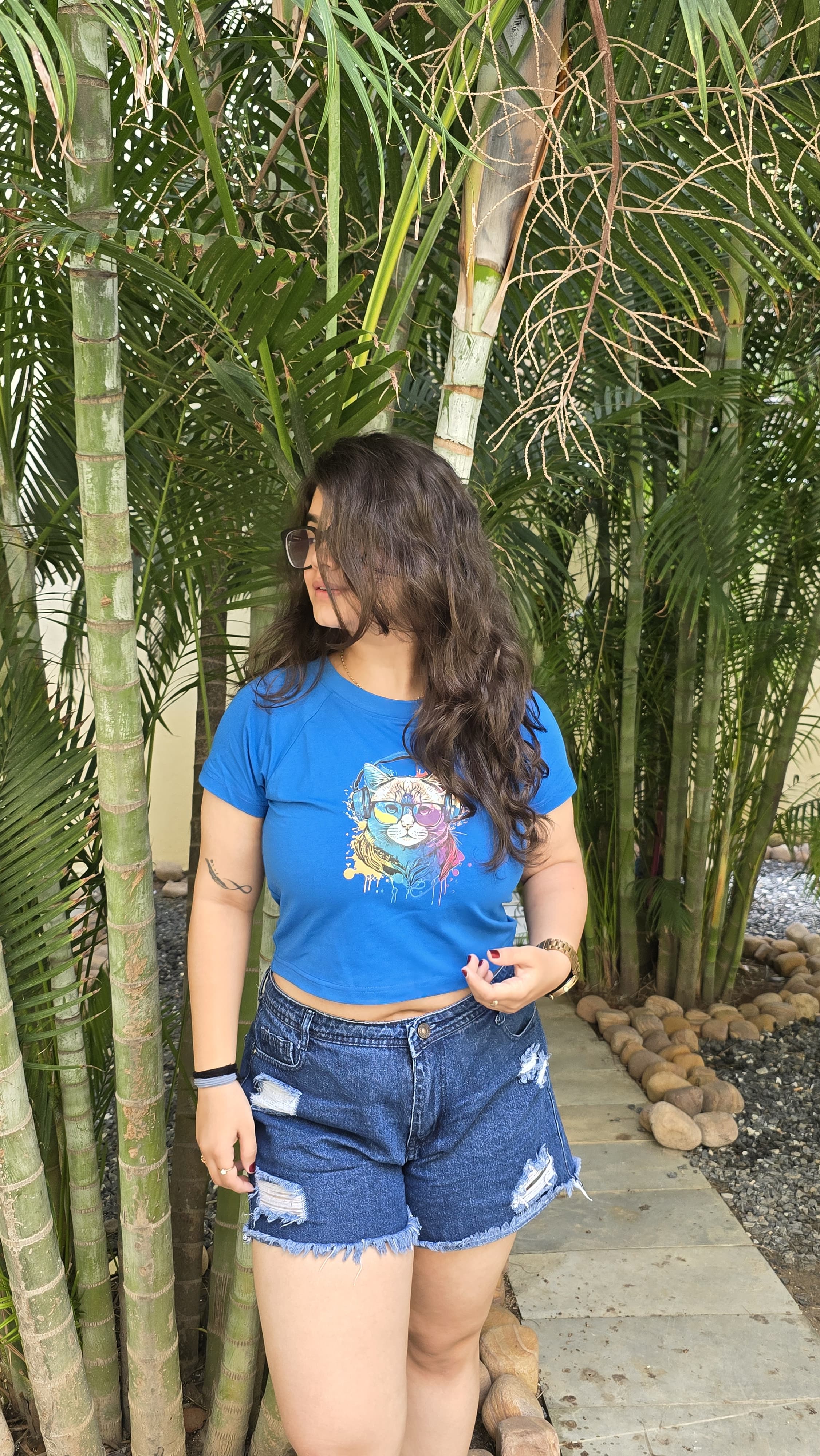Blue crop top with colorful cat wearing headphones and sunglasses graphic print, front view