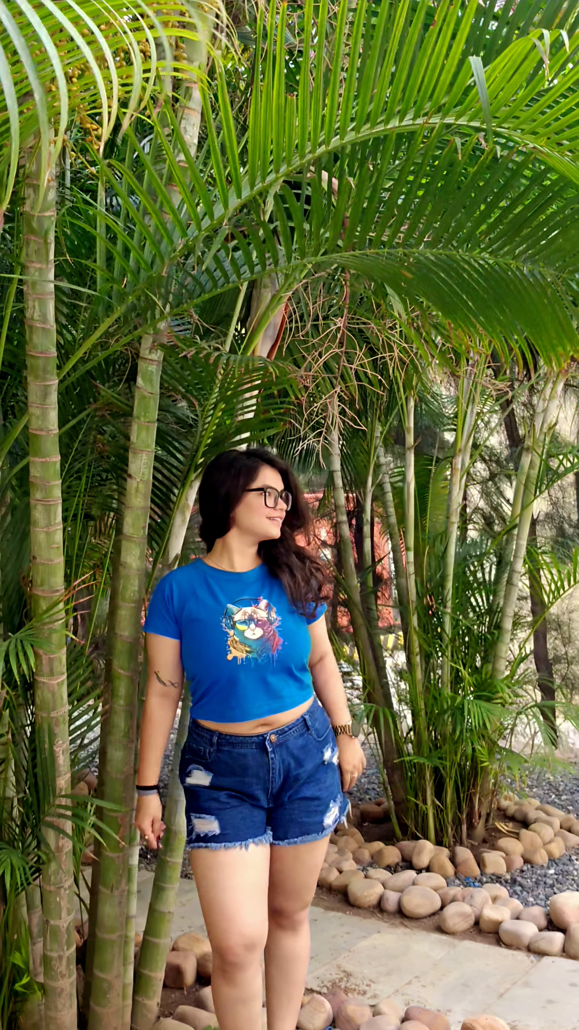 Blue crop top with colorful cat wearing headphones and sunglasses graphic print, front view