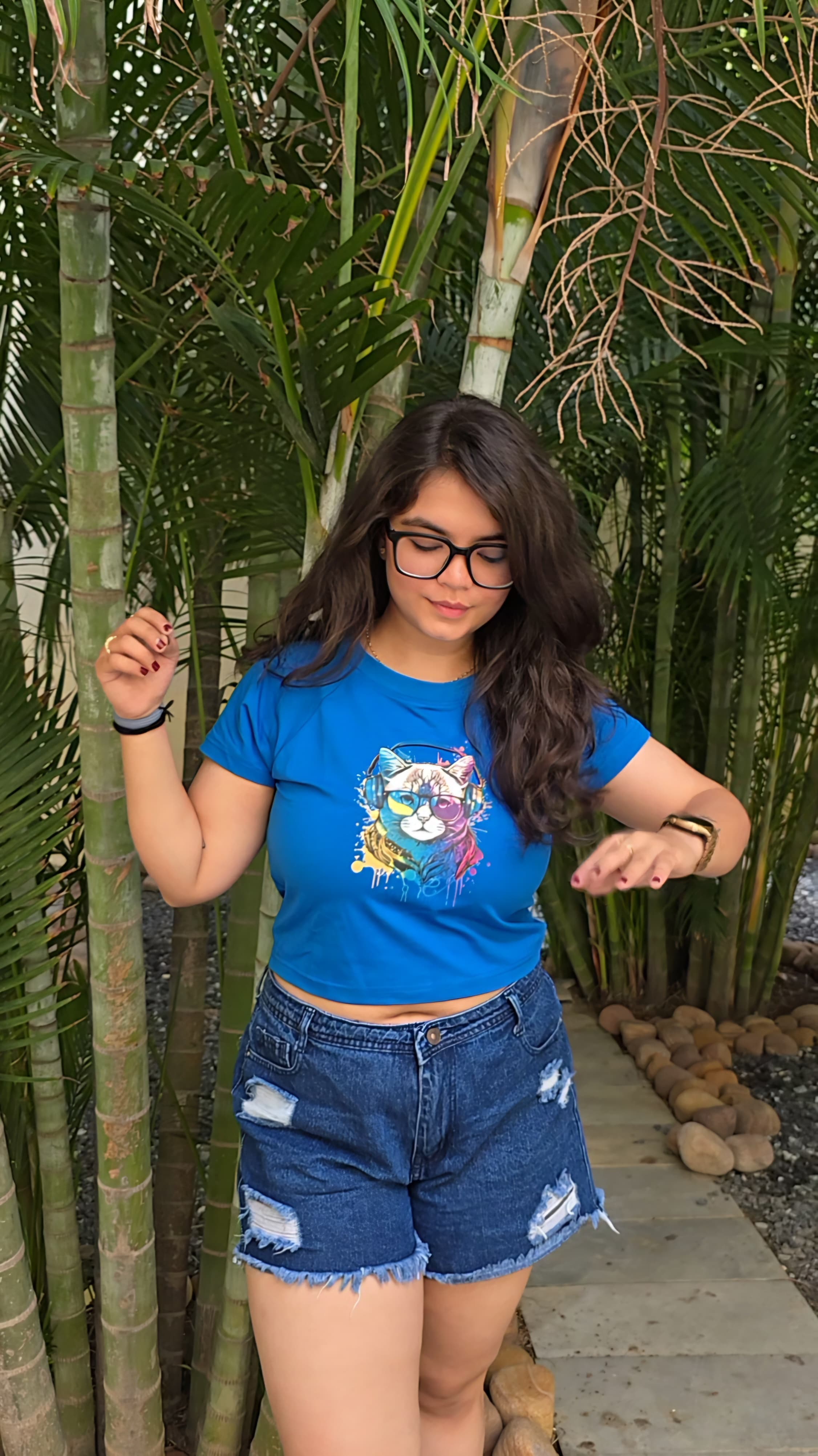 Blue crop top with colorful cat wearing headphones and sunglasses graphic print, front view